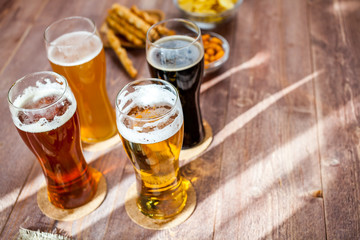 glasses of light and dark beer with assorted snacks on a wooden table background. bachelor party, pub, bar or degustation concept
