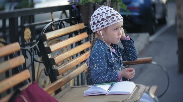 Little stylish beautiful gerl, on city streets listening to music in l headphones.