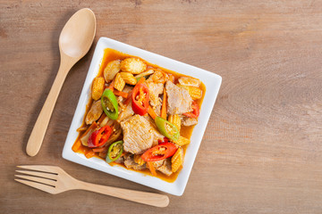 top view of stir fried pork with roasted chili paste in ceramic dish on wooden table. homemade style hot and spicy food menu.