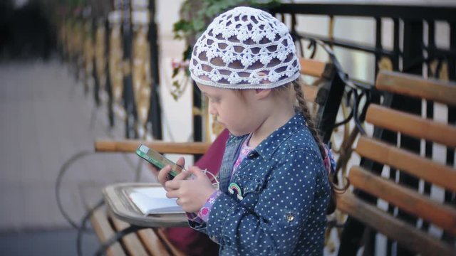 Little stylish beautiful gerl, on city streets listening to music in l headphones.