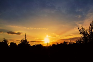 Photo sunset sky . Beautiful orange sky above dark forest at sunset .  Two suns 