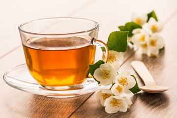 Glass cup of green tea with white jasmine flowers
