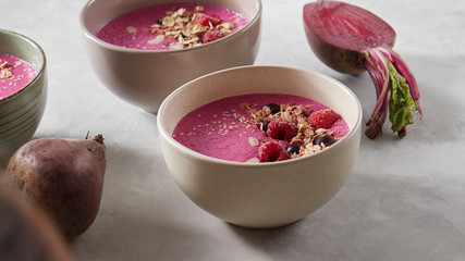 Obraz na płótnie Canvas Berry smoothie in a bowl on the breakfast with berries, oatmeal and honey on a stone background