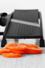 sliced tomato with mandoline on a grey wood kitchen worktop with selective colour