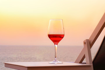 Two glasses of red wine on a background of sea horizon evening. Two glasses of red wine at sunset sea. Two Glasses of Red Wine Standing on Table at the hotel balcony. Toning