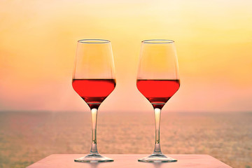Two glasses of red wine on a background of sea horizon evening. Two glasses of red wine at sunset sea. Two Glasses of Red Wine Standing on Table at the hotel balcony. Toning