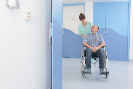 disabled man in wheelchair and nurse is pushing him