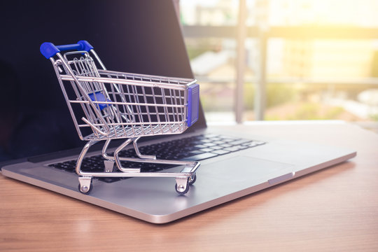 Small shopping cart on Laptop for shopping online with sunny background, Technology business online and e commerce concept.