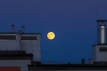 Fototapeta na wymiar Full moon over the house roof