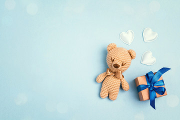 Toy bear and gift box on a blue background with copy space. Top view, flat lay.