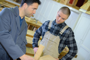 experienced carpenter teaching teenage boy