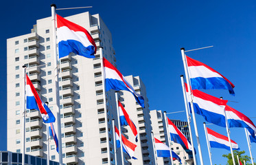 National flags of Netherlands against blue sky and modern building