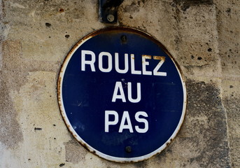 Roulez au pas. Panneau de signalisation routière rond, lettres blanches sur fond bleu.