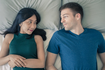 Couple with good communication skills.  White background laying on bed and happy.