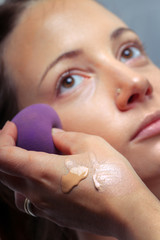 Applying foundation by sponge on face for make-up