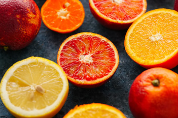 Mix of fresh ripe citrus fruits as blood oranges, mandarines, lemons on a blue stone background. Close up.