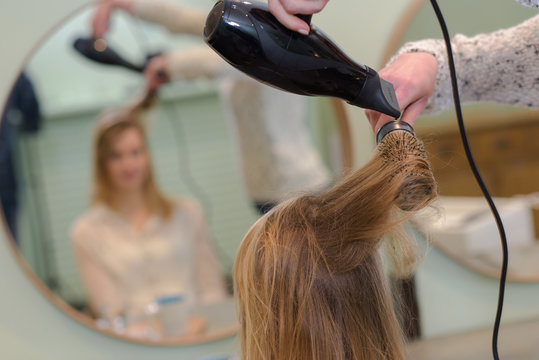 Hairdresser blow drying woman's hair