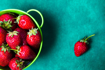 Strawberries in a bowl on green background