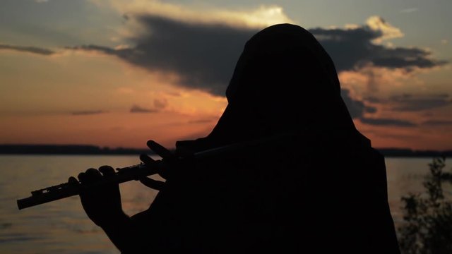 A Man Playing A Flute At Sunset