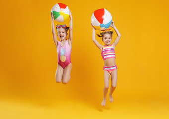 funny funny happy children in bathing suits  jumping  on colored background