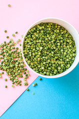 Dry uncooked green peas in a white bowl on duotone background. Top view and copy space.