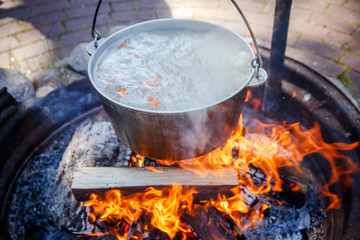 A cauldron with fish soup, which is cooked on a fire