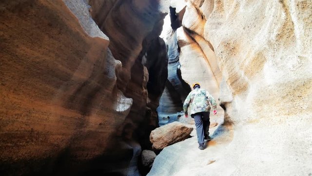 Older adventurer hiking on flowing shapes wall caves. Explore concept, 4k