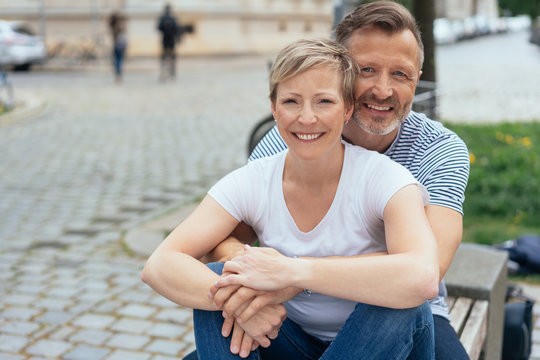 Happy middle-aged couple sitting on an urban bench