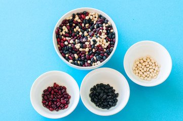 Tree types of dried beans in a white bowls on a light blue background. Top view. Healthy eating concept.
