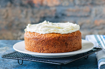 Homemade sour cream cake with cream cheese frosting on a white plate.