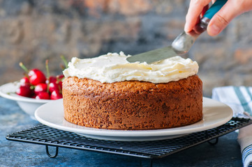 Woman decorating homemade sour cream cake with cream cheese frosting - 207727760