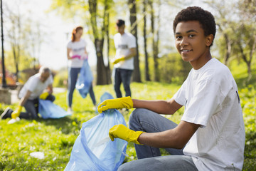 Volunteer opportunities. Attractive male volunteer using garbage bag while staring at camera