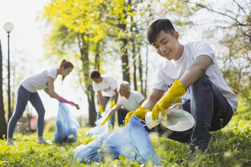 Careless people. Low angle of jolly male volunteer using garbage bag while holding litter