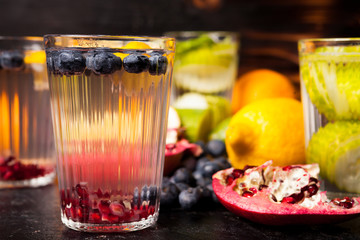 Organic detox water made from fresh natural berries, fruits and vegetables on dark vintage wooden background