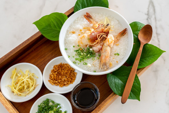 Beautiful presentation of Asian breakfast, congee with shrimp in wooden tray on white marble table