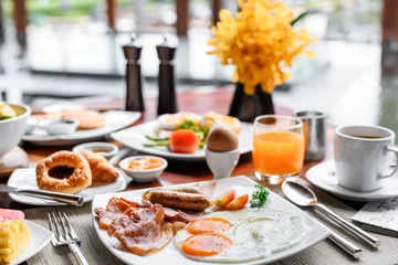 Foto op Aluminium Setting of breakfast includes coffee, fresh orange juice, eggs on table in hotel restaurant © 9mot