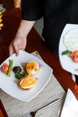 Concept picture, staff is holding a egg benedict for breakfast