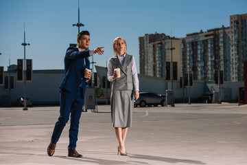 young attractive business couple with coffee to go on parking