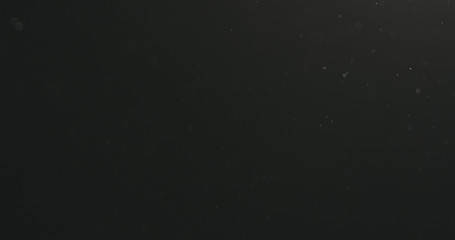 dust particles floating over black background with motion blur
