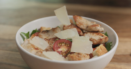 parmesan flakes falling on caesar salad