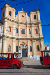 Plakat Tour buses in front of so called Trinitarian Church in historic part of Bratislava city, Slovakia