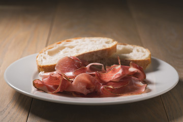 dried prosciutto ham on white plate