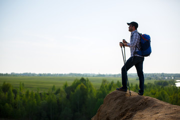 Image of tourist man with sticks for walking on hil