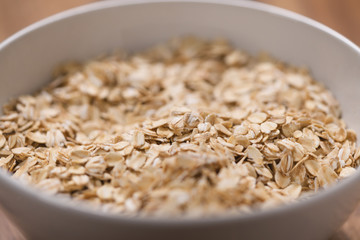 closeup oat flakes in white bowl with shallow focus