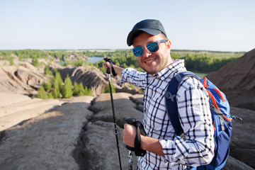 Image of tourist man with walking sticks showing hand forward in mountainous area