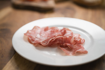 dried coppa ham on white plate