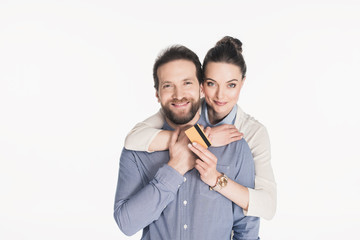 portrait of smiling woman with credit card hugging husband isolated on white