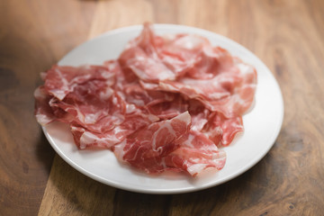 dried coppa ham on white plate