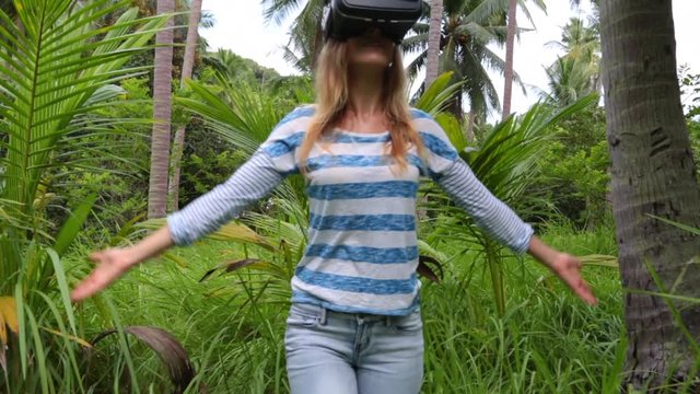 Virtual reality VR 3D headset and woman exploring the play on a background of nature jungle