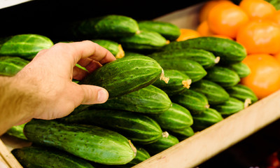 Man's hand selects fruits and vegetables from the supermarket shelves.